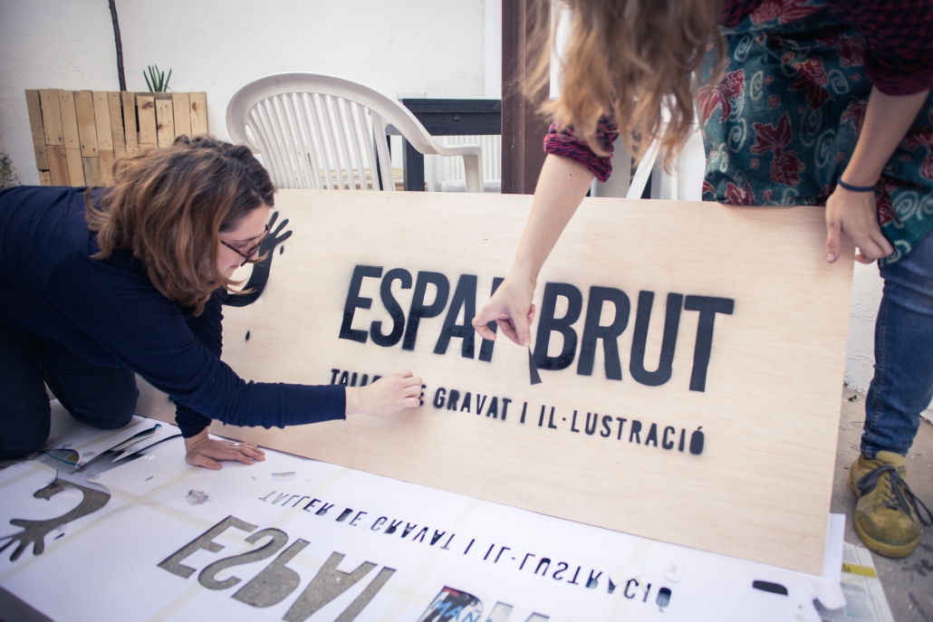 Two girls working on the wooden atelier sign